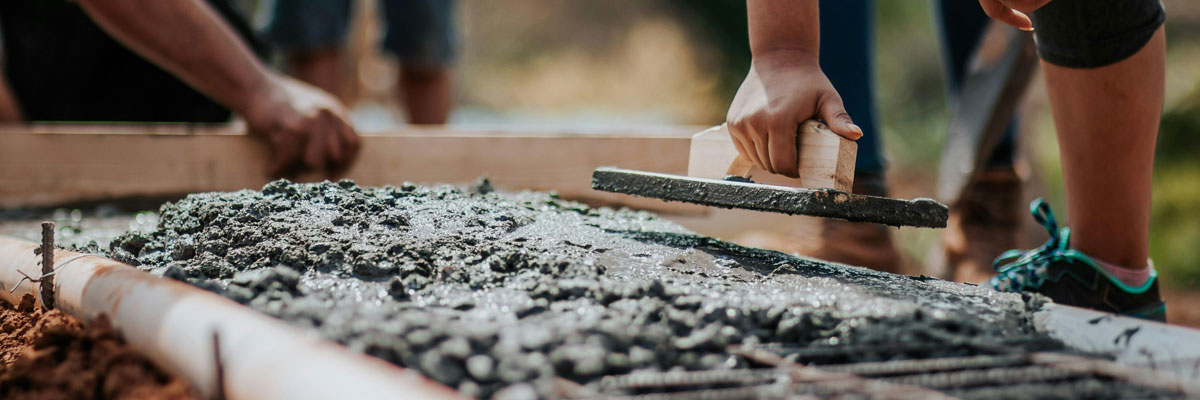 workers' hands smoothing out freshly poured concrete