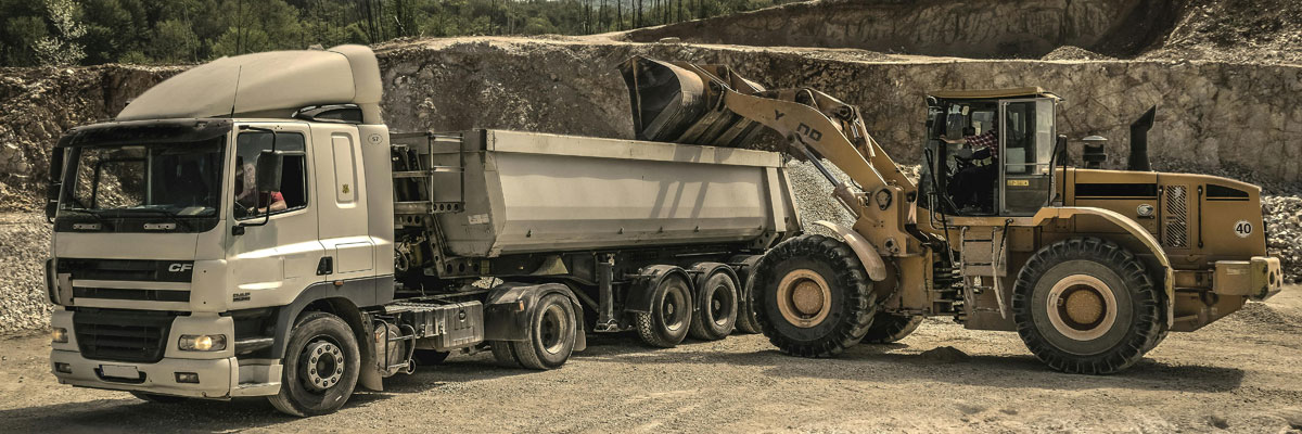 a large earth mover dumping dirt into a dump truck