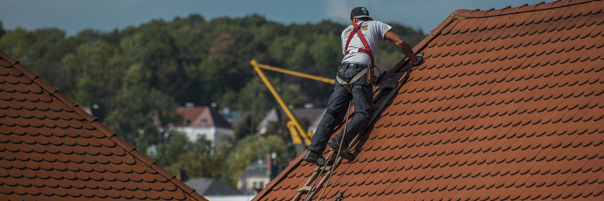 a man repairing terra cotta shingles on a roof