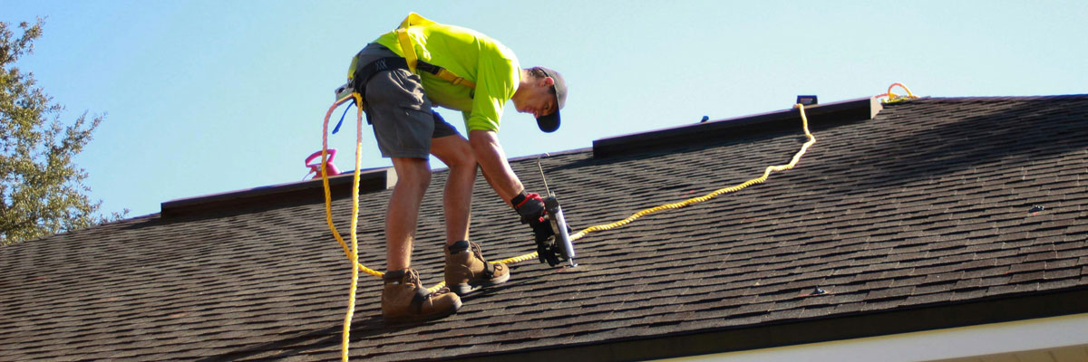 A man installing roofing shingles